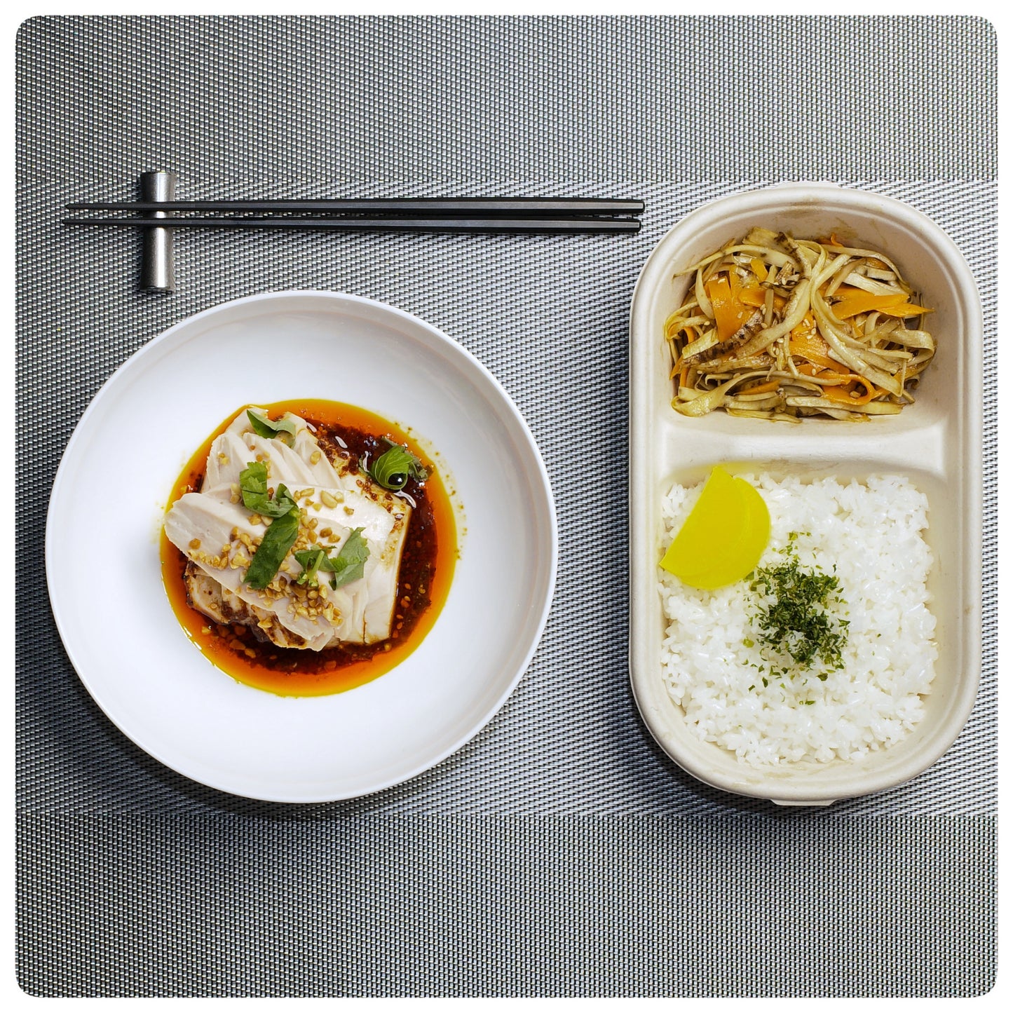 OKA-OKA meal with tofu in sauce, stir-fried vegetables, and white rice with pickled radish on a placemat