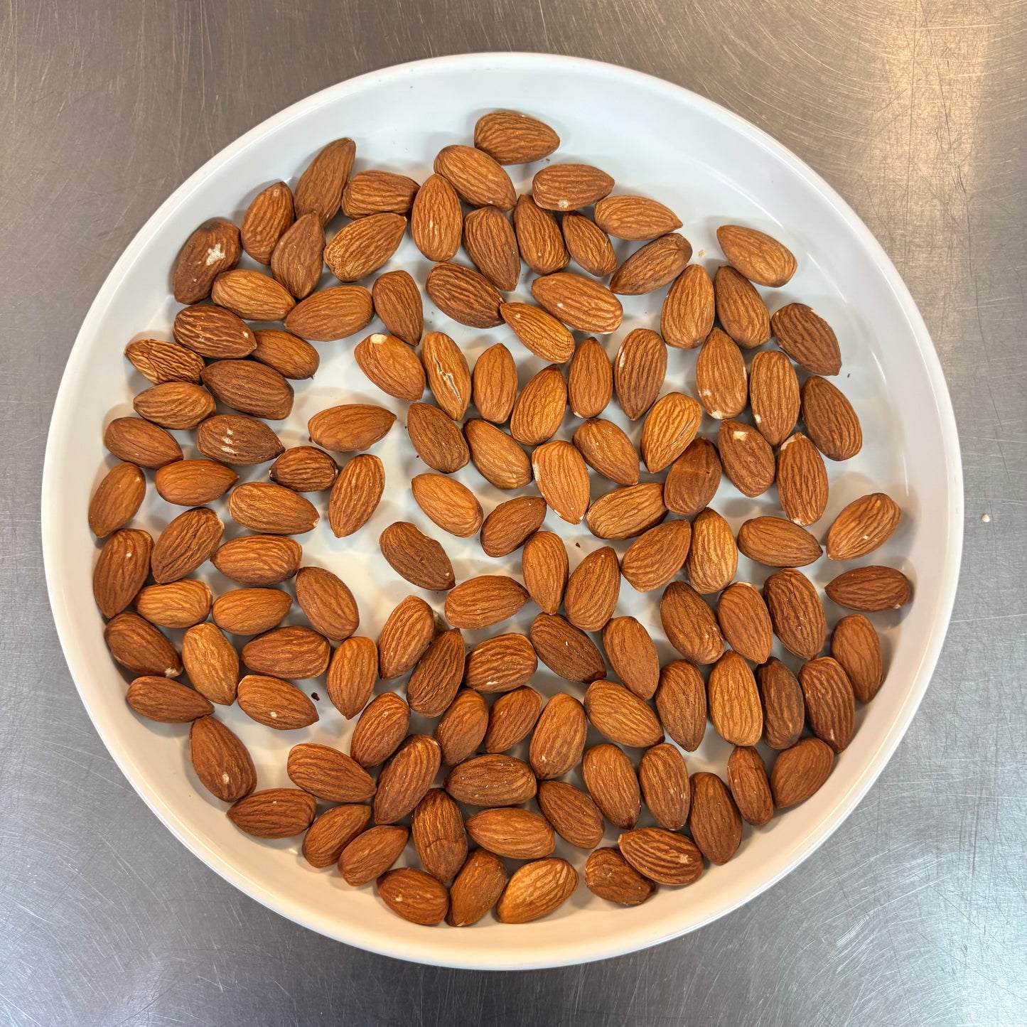 Fresh OKA-OKA roasted almonds in a white bowl, perfect for healthy snacking or cooking add-ons