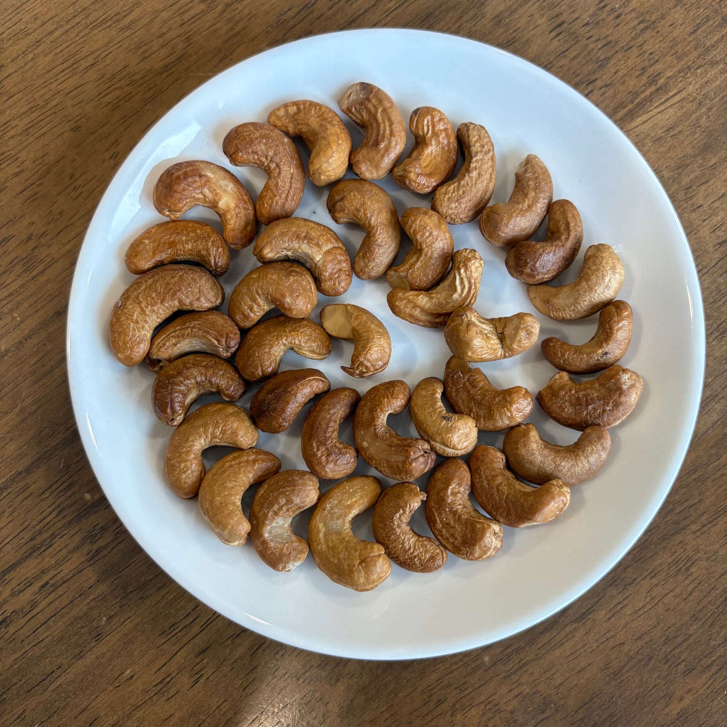 Healthy handcrafted cashews arranged on a white plate, perfect for snacking or cooking
