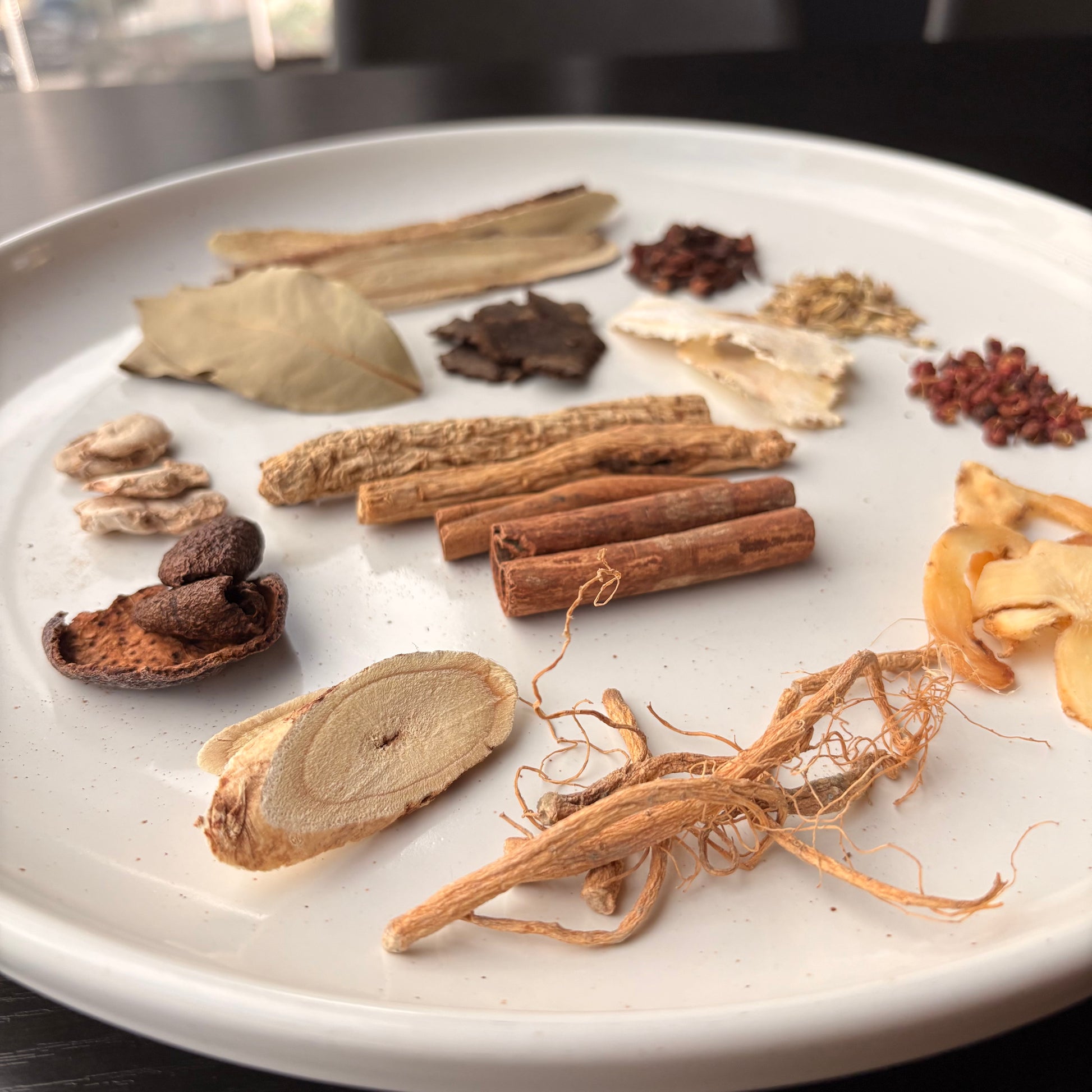 Selection of spices and herbs for herbal braised chicken leg preparation on a white plate