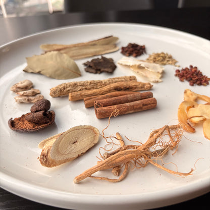 Selection of spices and herbs for herbal braised chicken leg preparation on a white plate
