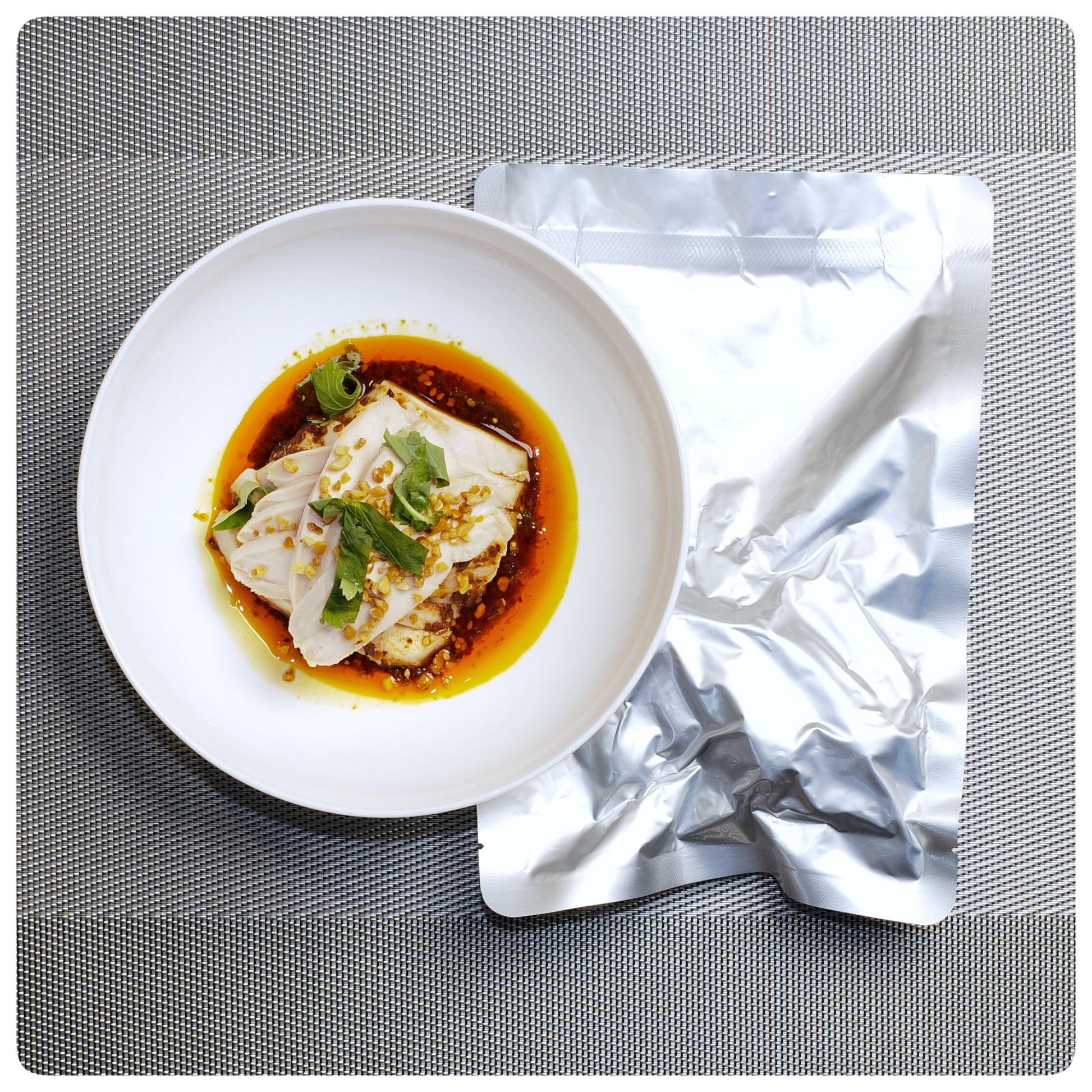 Sichuan-style mouthwatering chicken served in sauce with fresh herbs and scallions in a white bowl
